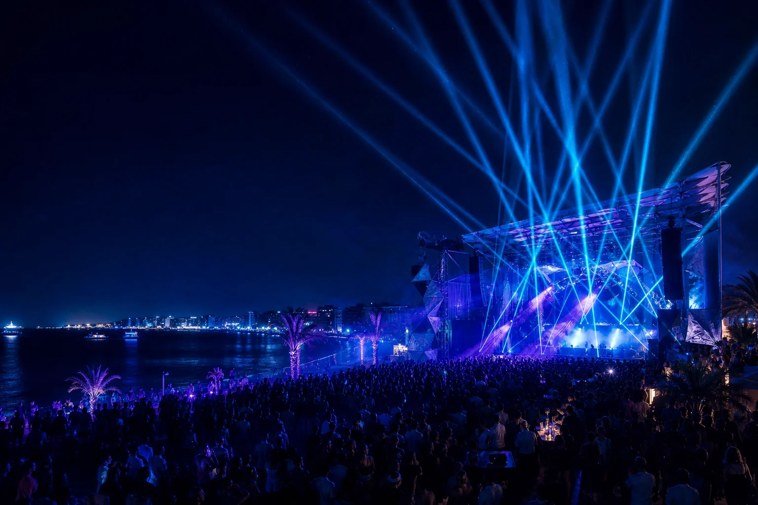 Große Open-Air-Bühne mit blauen Lasern am Meer bei Nacht